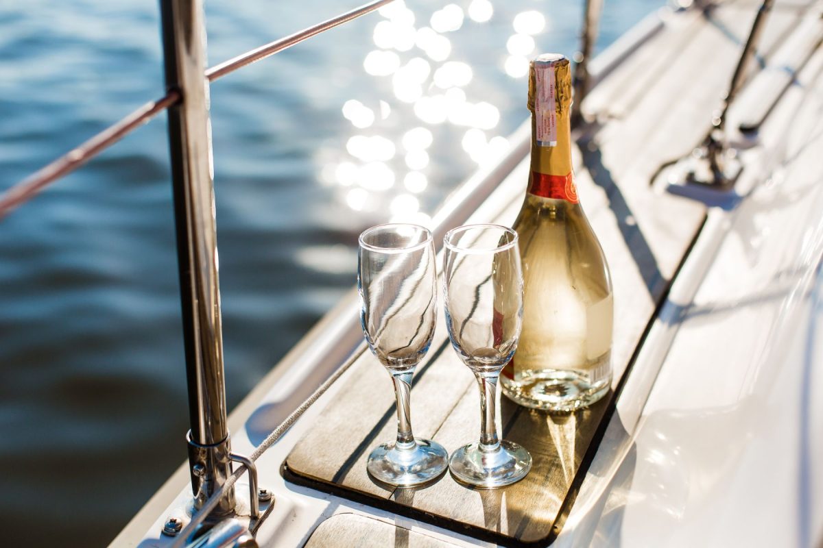 Two campaign glasses sit next to the edge of the boat with the water glistening below. 