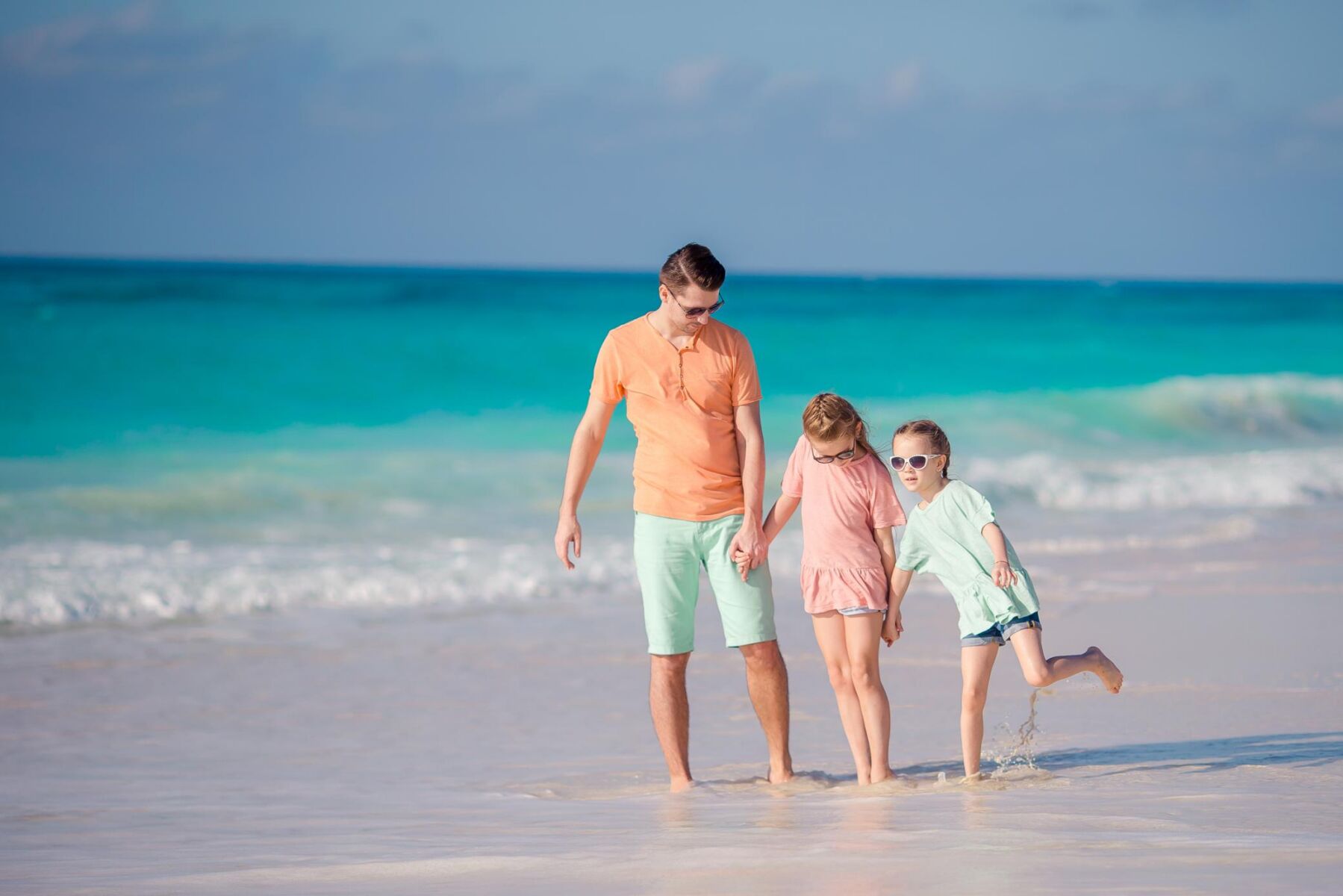 parent walking with kids on the beach