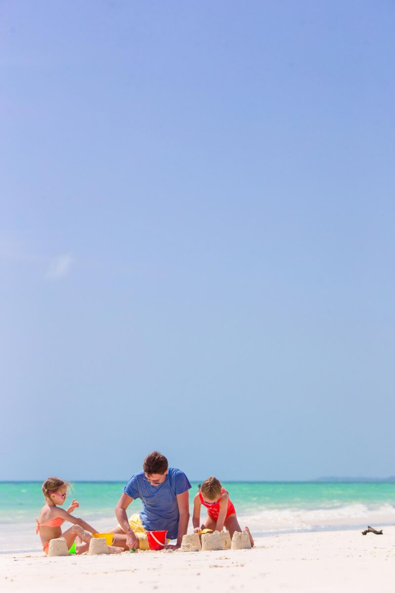 Father and kids making sandcastles on the beach